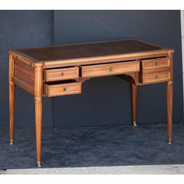 A handsome French writing table or desk in the Louis XVI style - featuring an embossed leather top set within a moulded,...