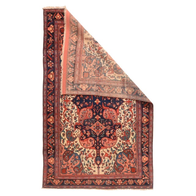 This well-preserved, finely knotted west Persian village scatter shows a sandy ivory field supporting a tall compound...