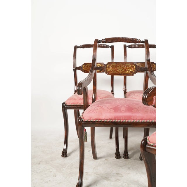 An absolutely gorgeous set of late-19th century regency-style dining chairs, of which two are armchairs. Intricate brass...