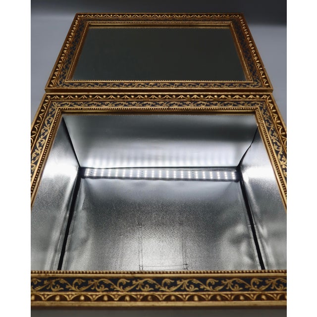 A handsome matched pair of decorative mirrors featuring a deep navy ground with gilt acanthus scrollwork, an inner beaded...