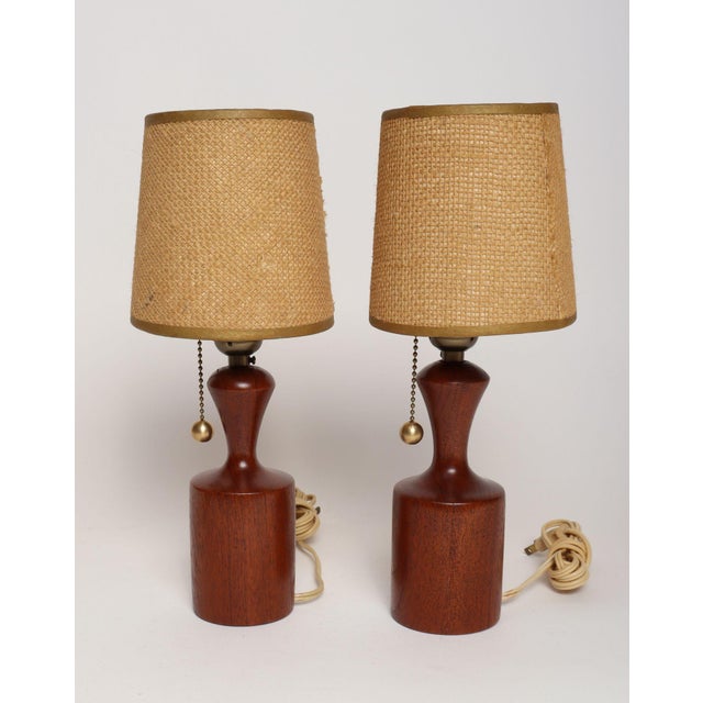 Petite, sculptural pair of solid teak table lamps (ca. 1960s, Denmark). Features a ball on/off pull string, brass sockets,...