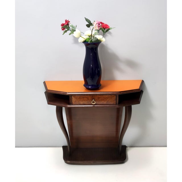 Made in Italy, 1950s. This console table is made in beech and walnut root and features an orange back-painted glass top,...