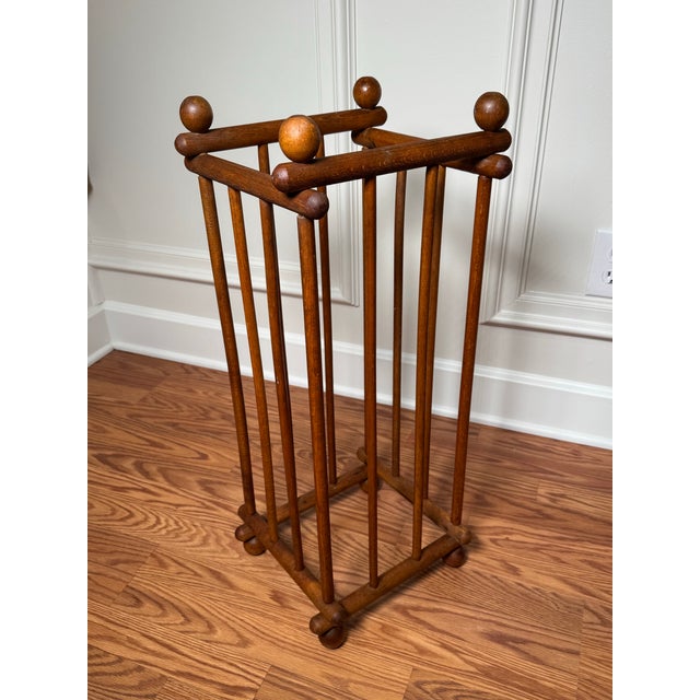 This tall, rectangular open framework umbrella stand is constructed of turned wood rods with ball finials on top, one at...