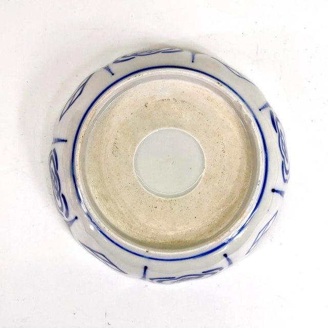 This is a beautiful Japanese Imari porcelain shallow bowl with paintings of plants and small trees