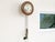 An antique wall mounted clock with a round mahogany case, Roman numeral enamel dial, brass hands and two weighted, chain-...