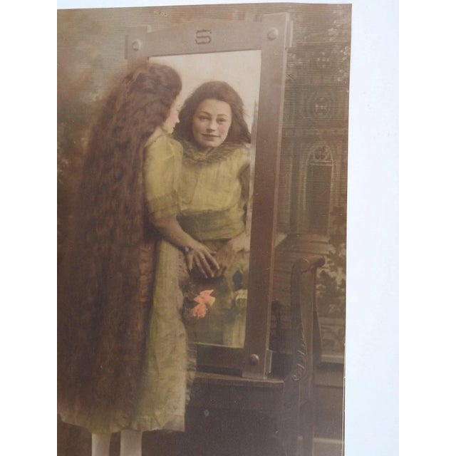 Vintage circa 1915 sepia toned and hand tinted studio photgraph or woman with extremely long hair looking into a mirror....