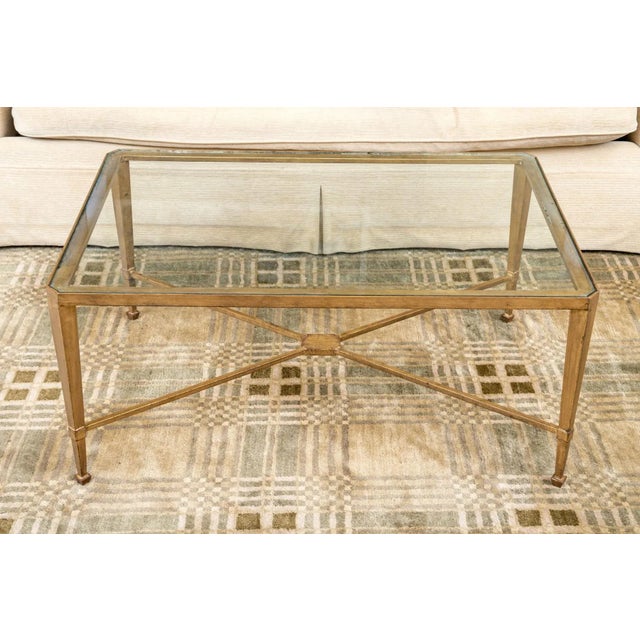 A very fine and perfectly-sized wrought iron coffee table with a heavy inset glass top, subtly canted corners, cross-form...