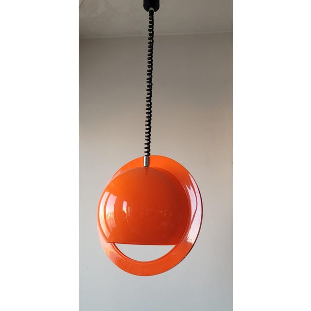 Iconic pendant lamp attributed to Guzzini, made of molded plastic with an all-orange finish. The diffuser features a...