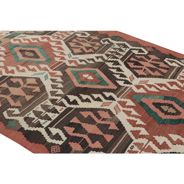 Handwoven in a wool flat weave originating from Turkey circa 1950-1960, this vintage Kilim rug connotes a mid-century...