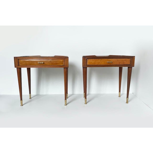 A unique pair of 1950s bedside tables by paolo buffa, made in italy. The tables feature wooden legs, a top with a drawer...