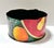 A vibrant vintage toleware cachepot hand-painted with oversized fruit, foliage, and bold blocks of red, yellow, green, and...