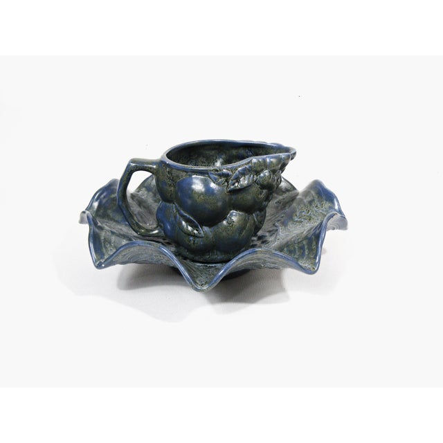 A charming vintage ceramic creamer and matching leaf-form dish in a soft mottled blue glaze, detailed with raised fruit...