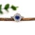A tanzanite sits in a deep violet-blue at the heart of this solid 14K white gold ring, framed by fourteen earth-mined...