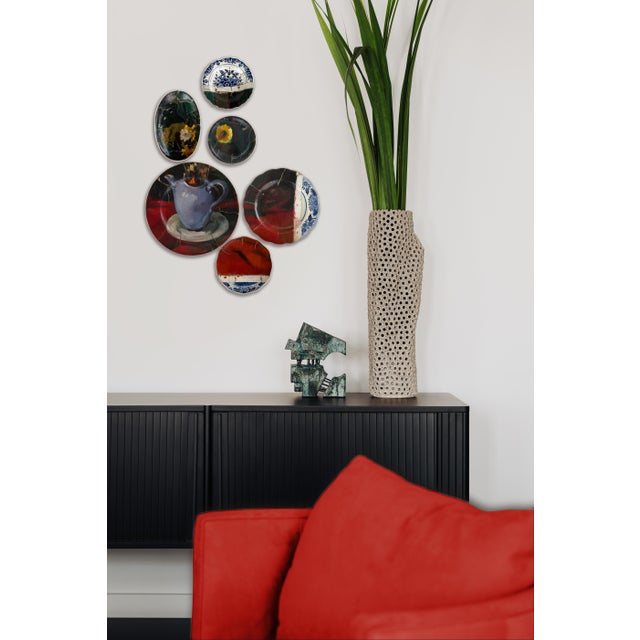 "Still Life in Red and Blue" consists of 6 plates combined with a painting of a bouquet in a light blue teapot on a bright...