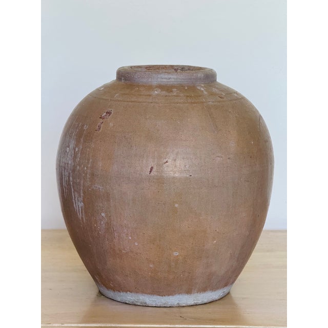 Two similar stoneware storage jars. One with a muted olive glaze and the other in a muted terracotta. The matt glaze is...