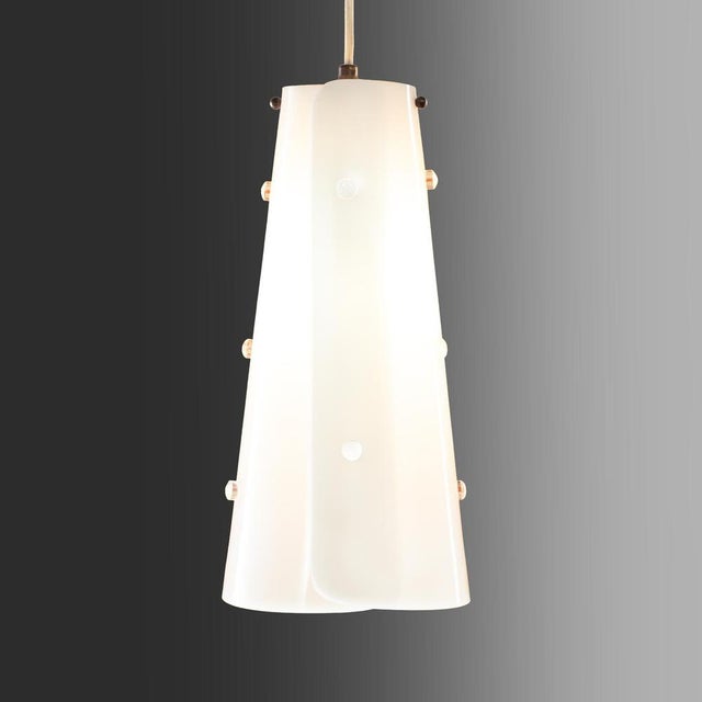 An extremely rare original pendant lamp from the 1960s featuring a conical white acrylic glass shade whose rim elegantly...