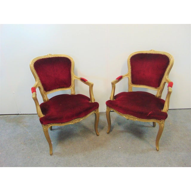 A pair or Louis XV style chairs with gold gilt painted finish, carved flower on crest, red velvet fabric with brass nail...
