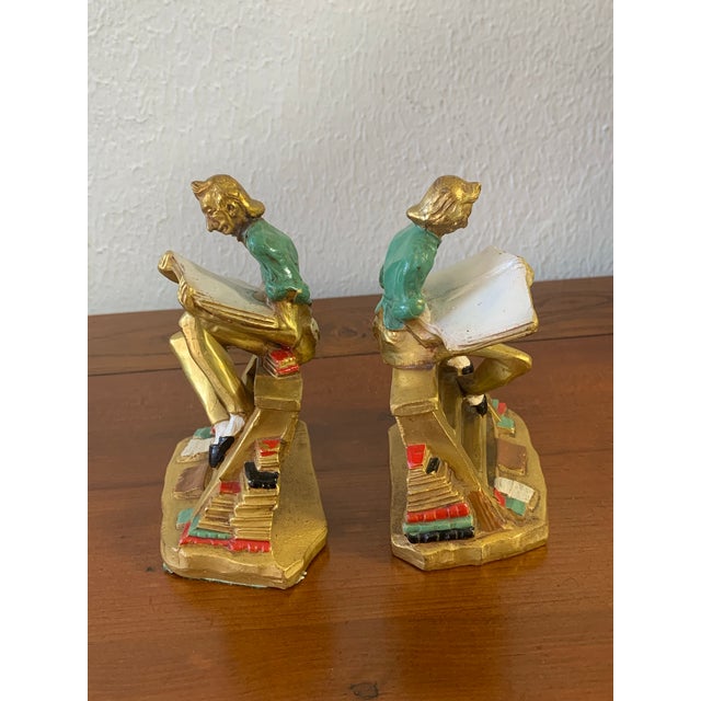 Charming vintage figural “Bookworm” cast iron bookends featuring a whimsical scholar/reader seated on stacked books while...