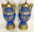 Cool pair of European Neoclassical hand painted porcelain urns from the 1920's. Each has a blue background with different...