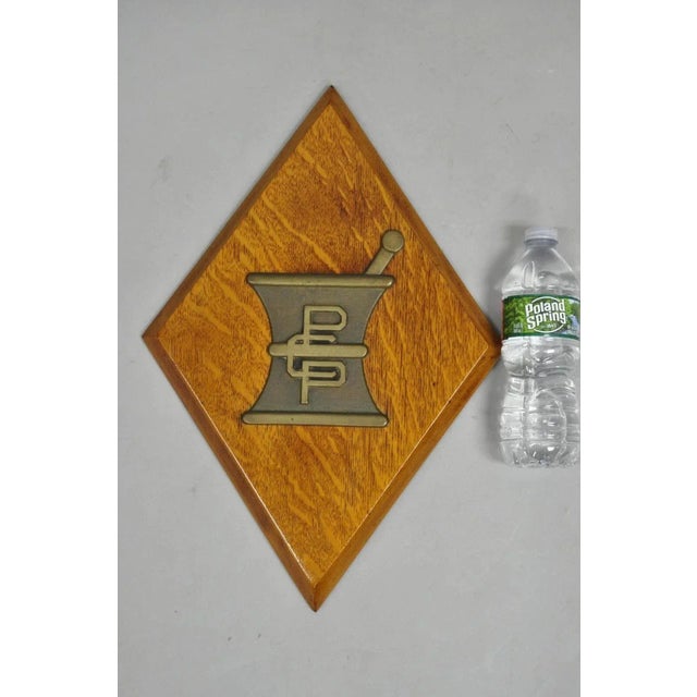 Antique Arts & Crafts Oak Pharmacy Apothecary Bronze Mortar & Pestle Wall Plaque. Circa Early 20th Century. Measurements:...