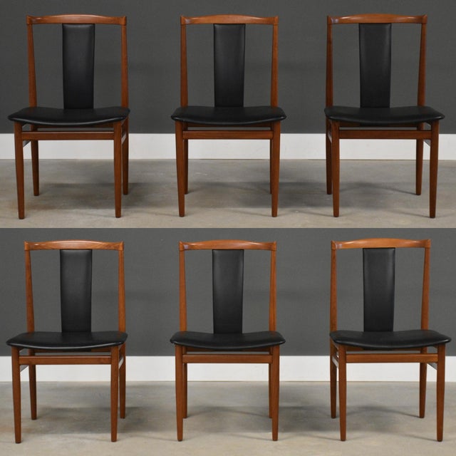 A set of six mid century modern solid teak dining chairs with black vinyl back rests and seats designed by Henning...