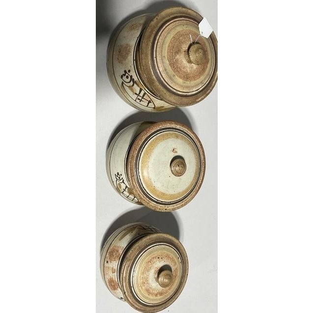 Signed by Lemonier. A distinctive set of three mid-century stoneware kitchen canisters featuring warm beach-sand glazed...