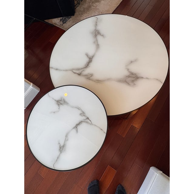 Elegant set of modern nesting coffee tables by Howard Elliott, featuring white marble-effect glass tops with soft, natural...