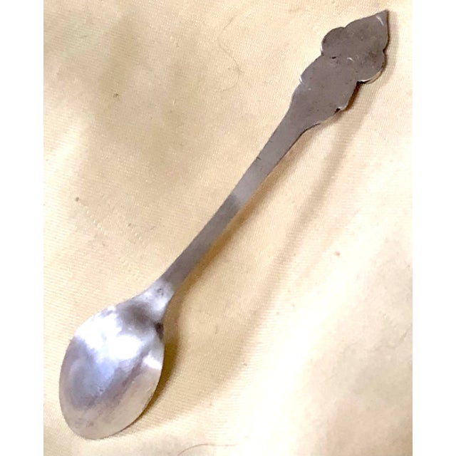 Tiny silver salt spoon with Asian deity on handle. Likely a tourist memento. No marks.