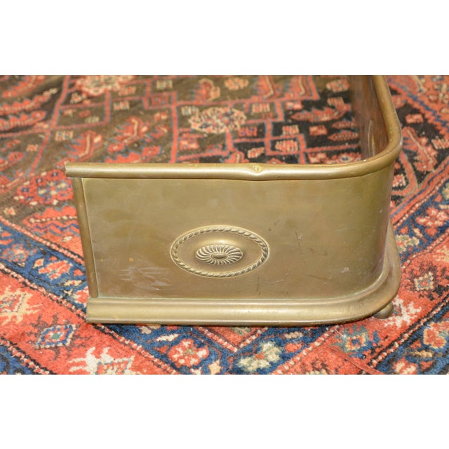 Great little curved brass fireplace fender. Purchased in the UK. Oval emblems around. 2 small flat feet in front. A good...