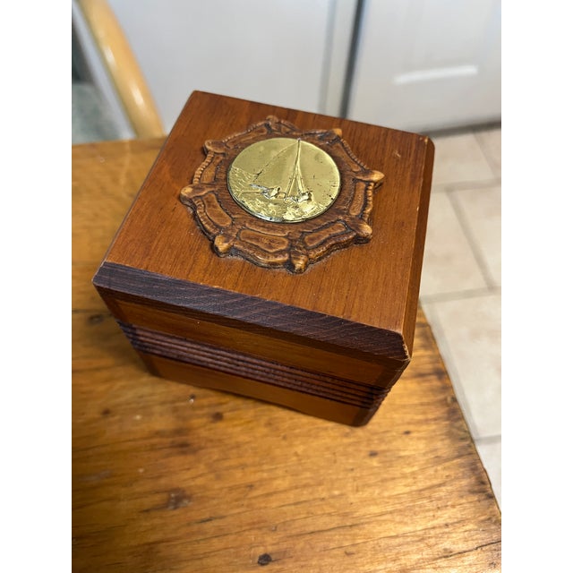 Carved warm wood with gold/brass nautical seal, gold sail boat with wooden carved rope wreath sticker on bottom reads...