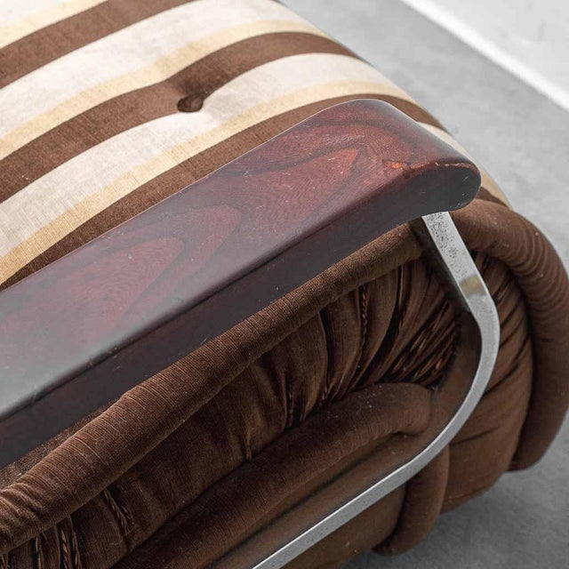 Armchair made in the 1970s. Brown fabric upholstery with wooden armrests and metal details. Plastic legs and base. Good...