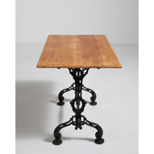 An early example of French bistro furniture featuring a decorative cast iron base designed for strength and daily use. The...