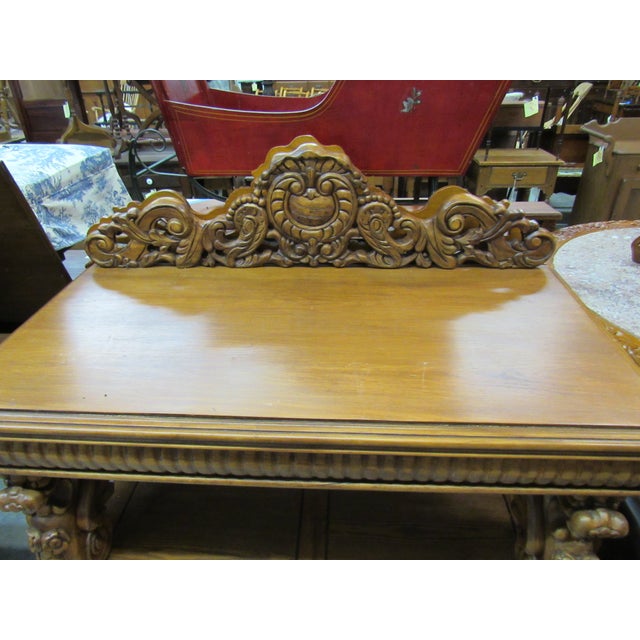 An impressive traditional wood console table featuring elaborate carved detailing and a substantial architectural design....