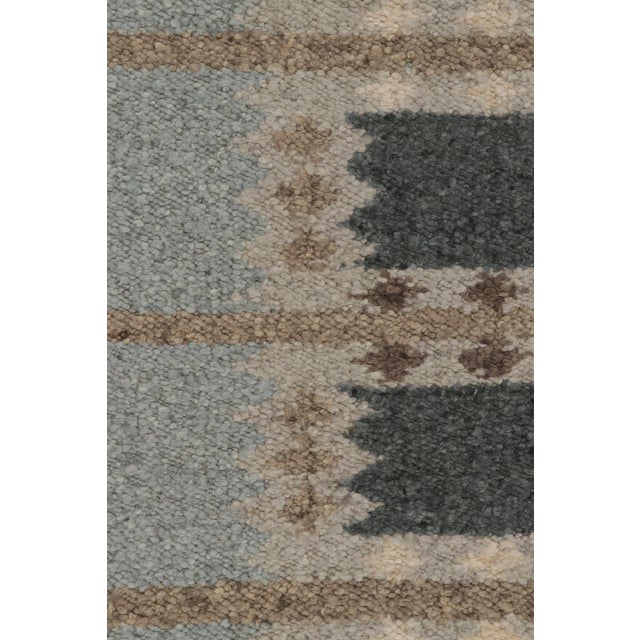 Hand-knotted in wool, this 10x11 Scandinavian rug features repeating geometric motifs in muted blue, taupe, and ivory....