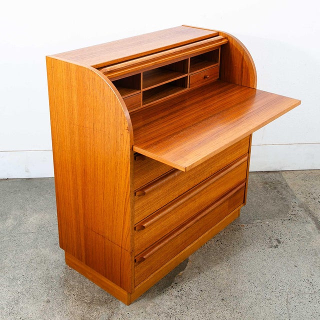 Danish Modern Secretary desk in teak with slide out desk surface. Rolls open and close easily. The piece offers 4 large...