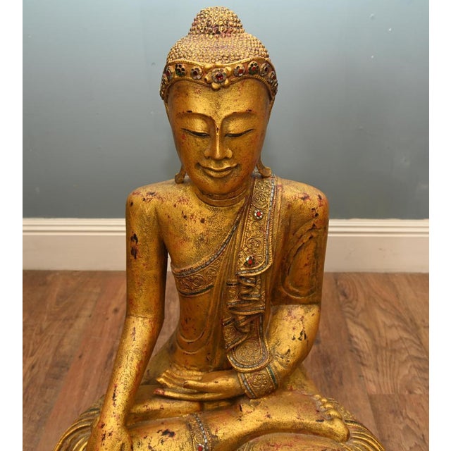 A striking antique Burmese gilt Buddha sculpture from Myanmar, depicted seated in the classic lotus position with a serene...