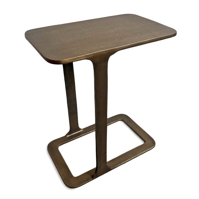 Modern cast aluminum end table with a warm antiqued brass finish. Its sculptural cantilever silhouette offers a refined...