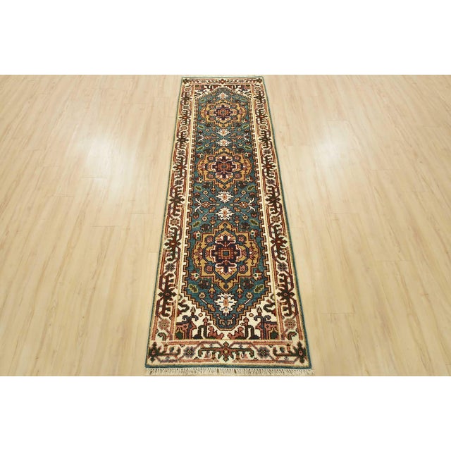 A traditional tribal Heriz runner hand-knotted with an all-wool pile on a cotton foundation. This oriental rug features...