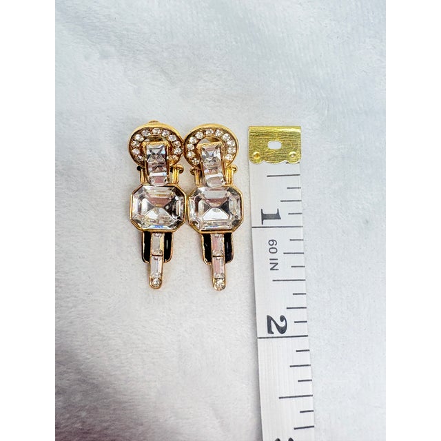 Elegant signed GIVENCHY (C) New York–Paris clip earrings featuring a large emerald‑cut clear glass center stone framed by...