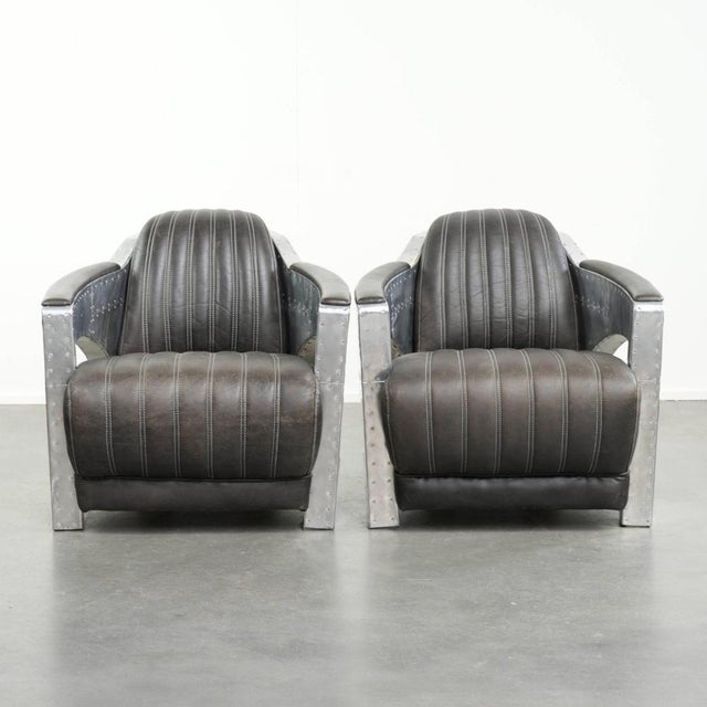 This set of 2 rugged industrial black cowhide Aviator design armchairs is finished with aluminum and rivets. They feature...