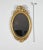 Charming oval mirror in golden wood with Louis XVI style, made up of a beveled mercury ice cream and topped with a...