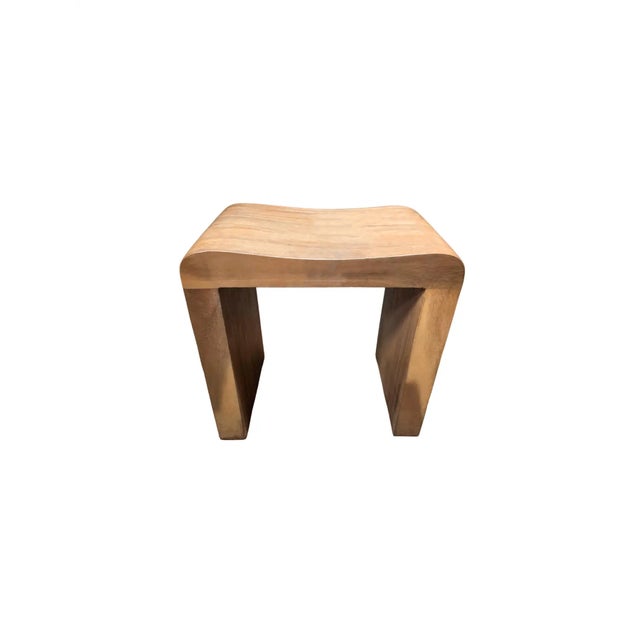 A wonderfully sculptural teak wood stool featuring a curved seat. The mix of wood textures and shades adds to its charm....