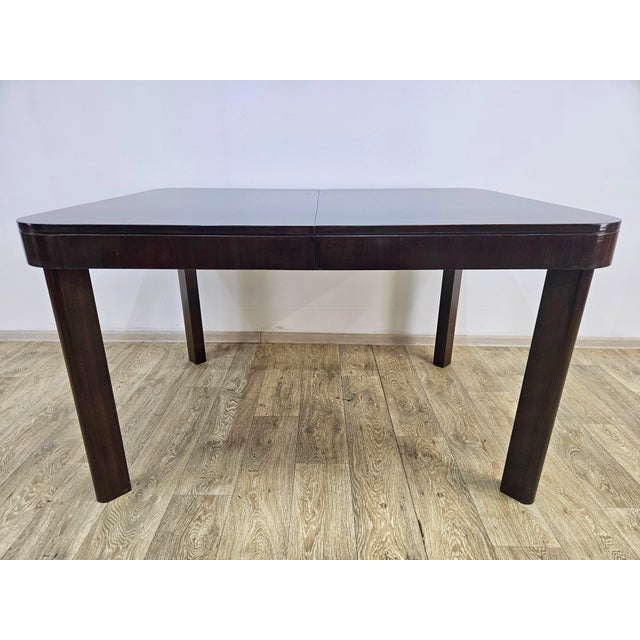 A very elegant art deco dining table from the 1950s. Made entirely of wood, veneered with high-gloss rosewood. Preserved...