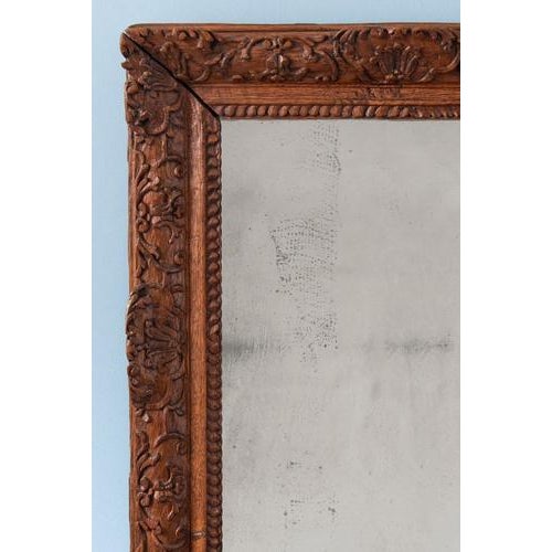 This early 18th-century French oak mirror is richly carved with seashells, flowers, foliage, and graceful scrolls, while...