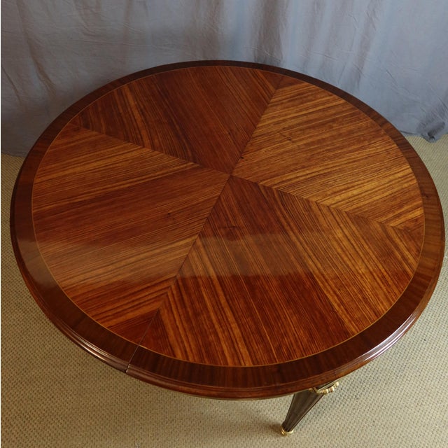 Large marquetry dining table with gilt bronze mounts. This table has two extension leaves with matching marquetry bands....