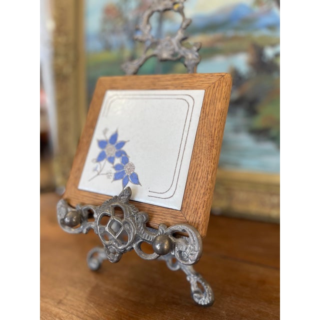 This vintage decorative tile features a hand-glazed blue floral motif set against a crackle-finished ivory ceramic...