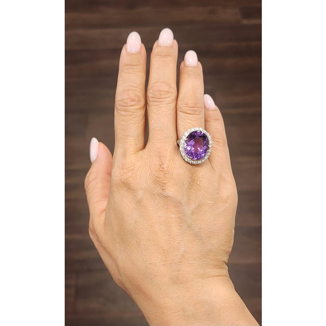 An approximately 16.0-carat amethyst takes center stage, displaying a rich purple hue in an oval cut. Surrounding the...