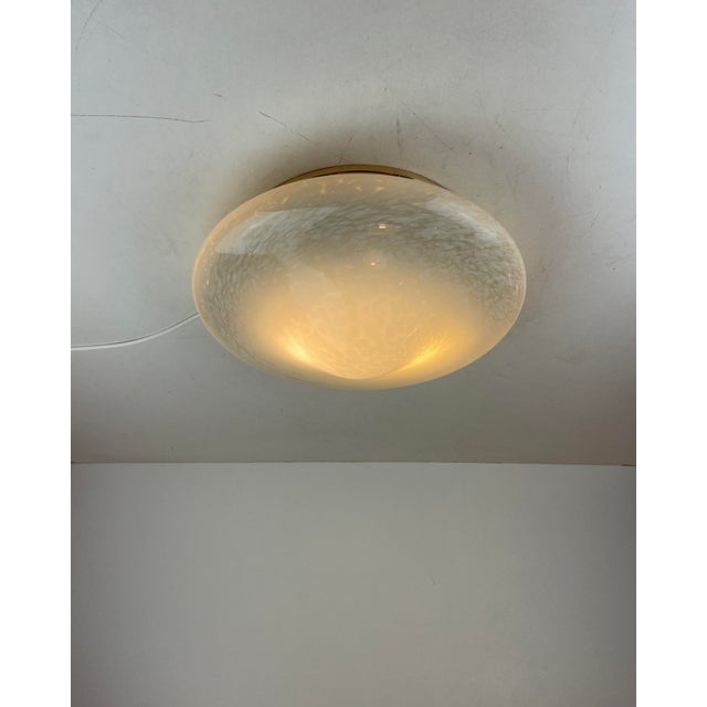 Flush-mount light with a clear Murano glass diffuser made in the ‘Vetro Maculato’ technique (white spot) and hung on a...