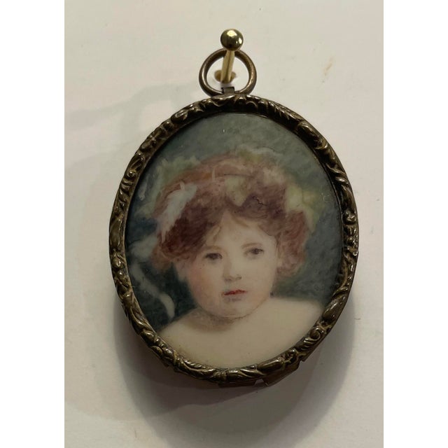 Antique portrait miniature of a child with flowers in her hair. Unsigned and mounted in a metal case to display or wear as...