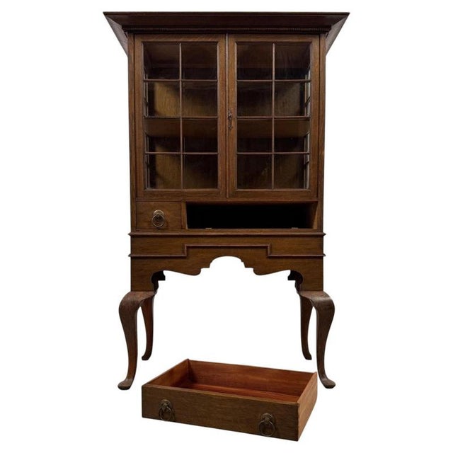An elegant English oak display cabinet dating from the early 20th century, beautifully constructed and distinguished by...